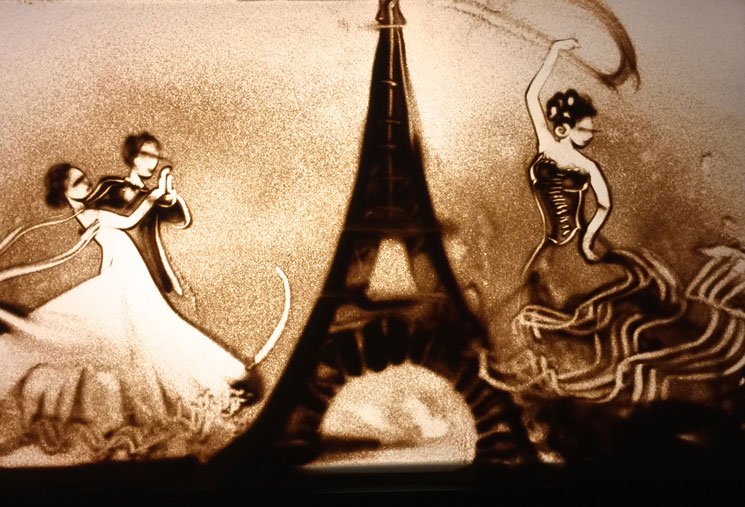 Sandbild von Tänzern neben dem Eiffelturm
